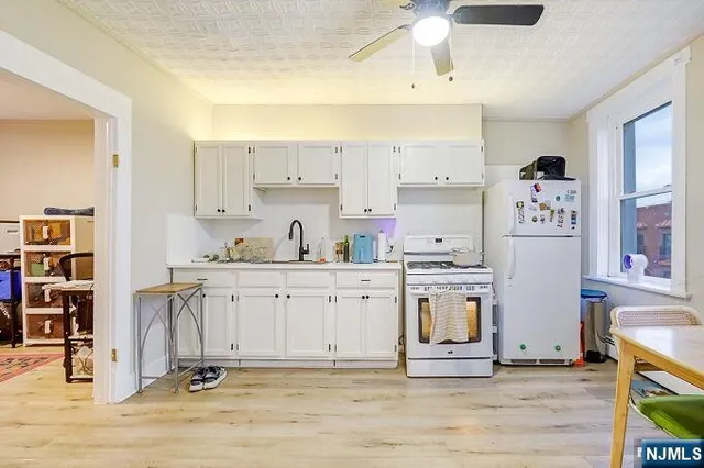 a kitchen with stainless steel appliances white cabinets and wooden floor