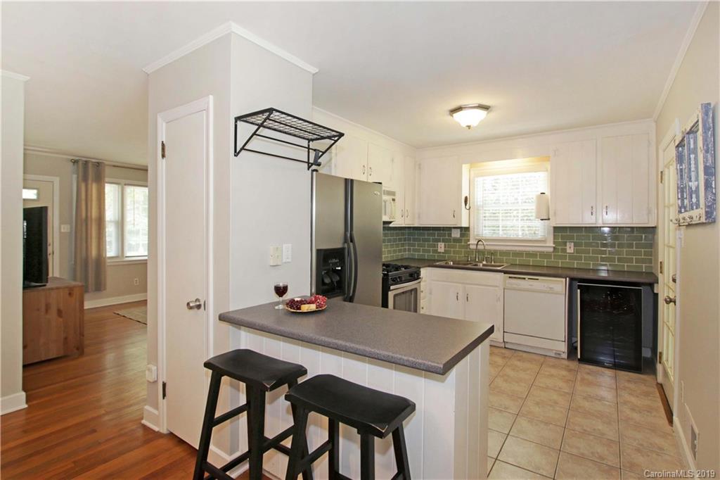 4137 Applegate Road Charlotte, NC 28209 - Photo 12 of 44 a kitchen with stainless steel appliances kitchen island granite countertop a refrigerator a stove and white cabinets with wooden floors