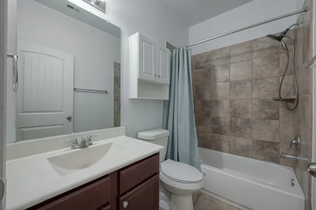 an empty room with chandelier fan and windows