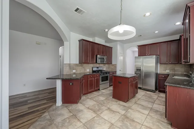 a kitchen with stainless steel appliances granite countertop a stove a sink a microwave and a refrigerator