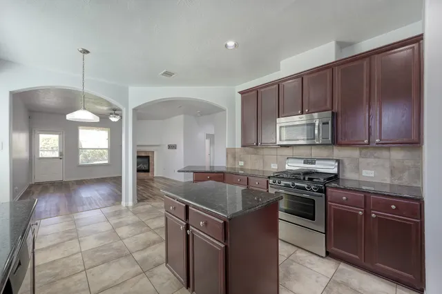 a large kitchen with stainless steel appliances granite countertop a sink counter space cabinets and a large window