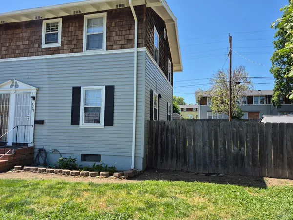 a view of a house with a yard and wooden fence