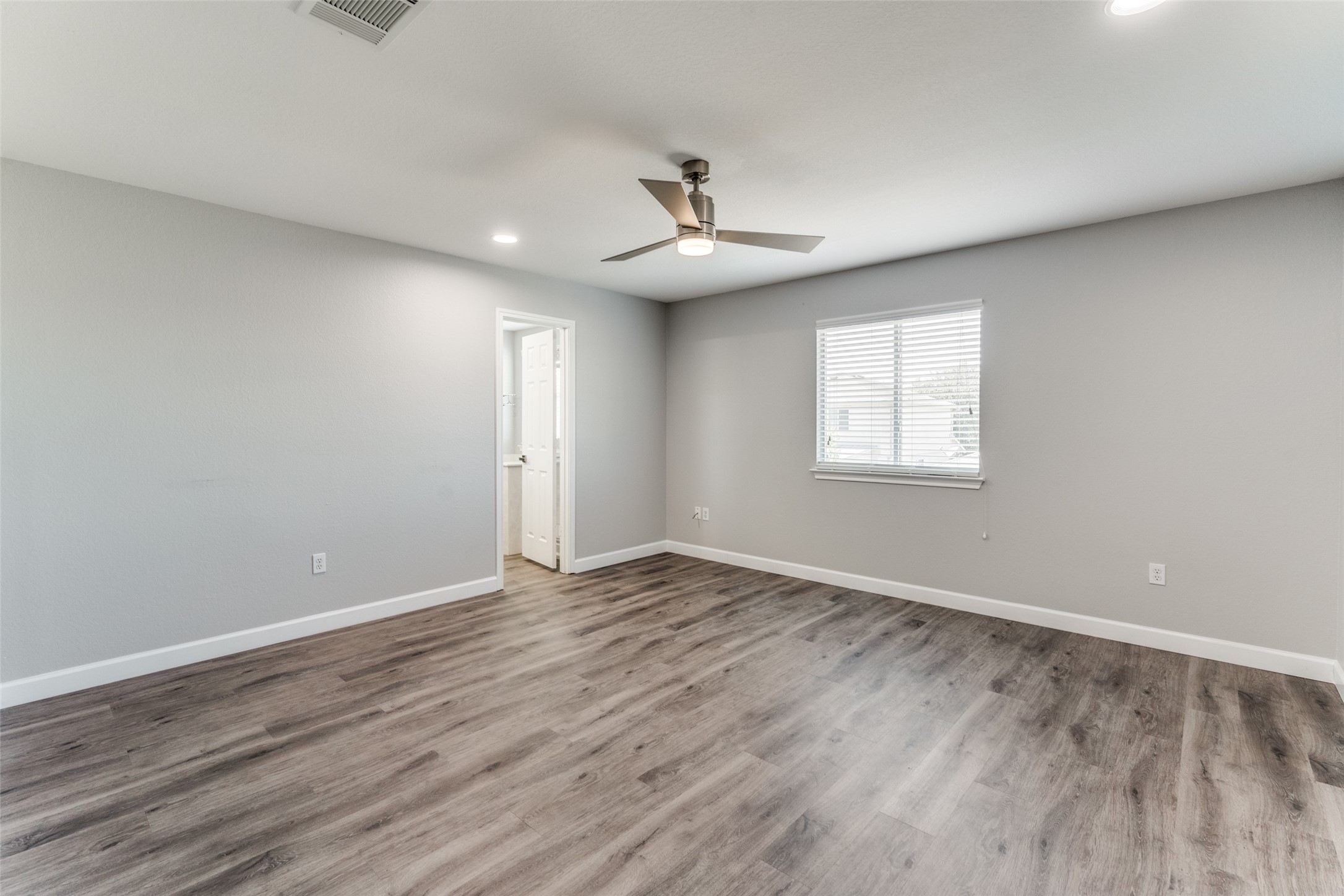 1408 Poppy Seed Lane Austin, TX 78741 - Photo 14 of 23 an empty room with wooden floor ceiling fan and windows