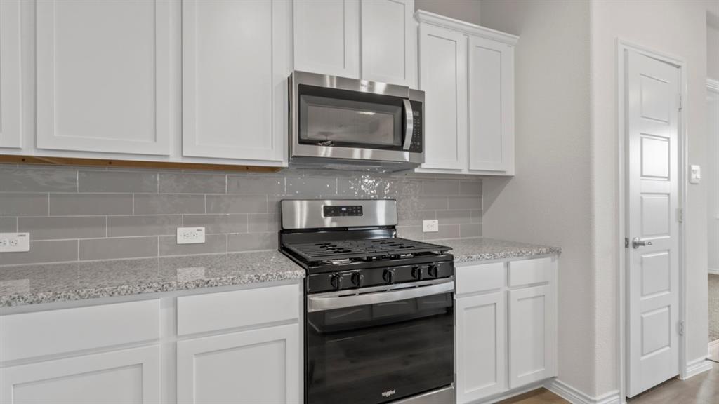 510 Range Road Caddo Mills, TX 75135 - Photo 18 of 25 Kitchen with stainless steel appliances, white cabinetry, light stone countertops, and decorative backsplash