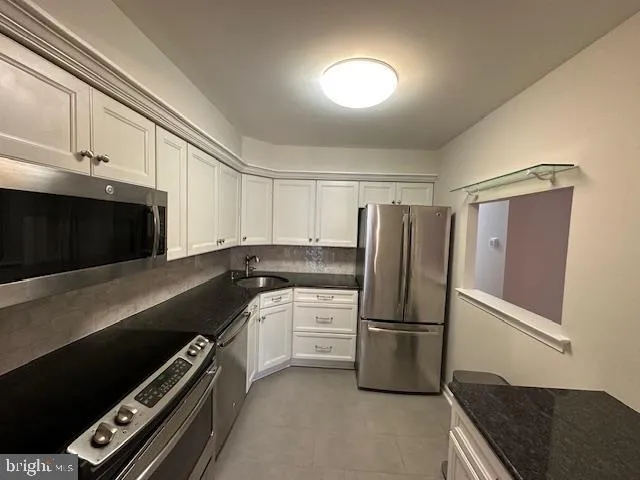 a kitchen with granite countertop a refrigerator and a stove top oven