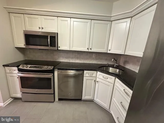 a kitchen with white cabinets and stainless steel appliances