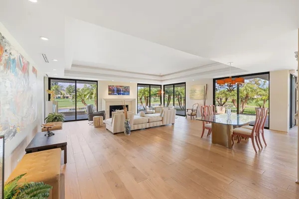 a living room with furniture large windows and wooden floor