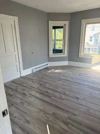 a view of empty room with window and wooden floor