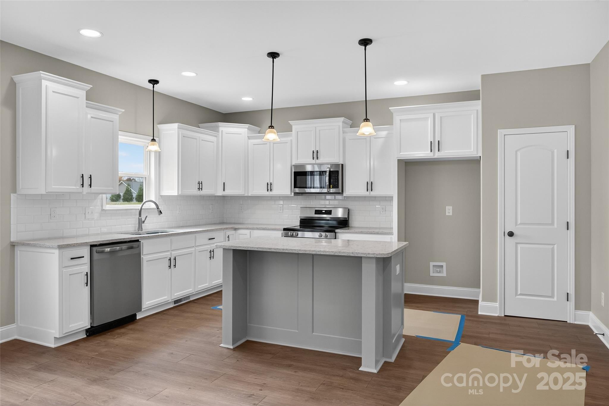 7195 Mooresville Road Salisbury, NC 28147 - Photo 12 of 38 a kitchen with stainless steel appliances granite countertop a sink a stove a refrigerator and white cabinets with wooden floor