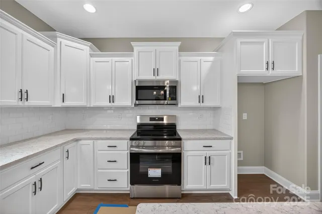 a kitchen with white cabinets and appliances