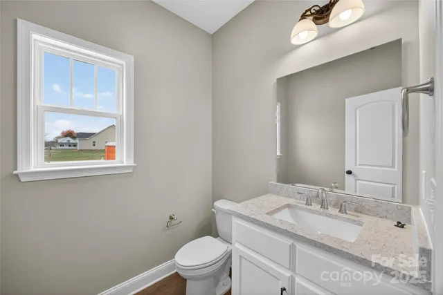 a bathroom with a granite countertop toilet a sink and mirror