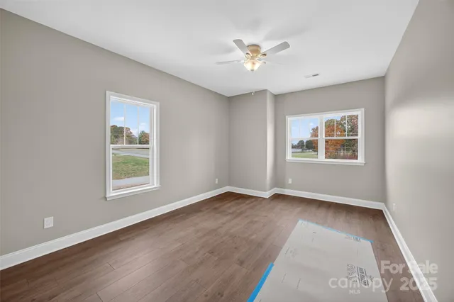 a view of an empty room with a window and wooden floor