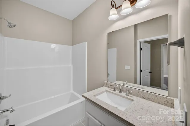 a bathroom with a granite countertop bathtub sink vanity and mirror