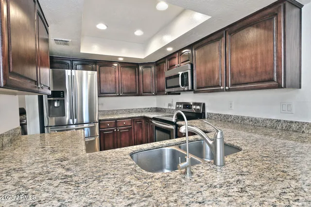 a kitchen with stainless steel appliances granite countertop a sink refrigerator and cabinets