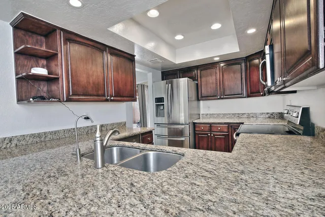 a kitchen with stainless steel appliances granite countertop a sink stove and refrigerator