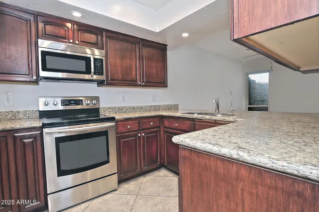 a kitchen with stainless steel appliances granite countertop wooden cabinets stove and microwave