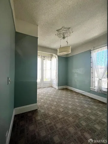 en empty room with windows and chandelier