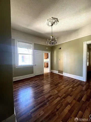 a view of empty room with wooden floor and window