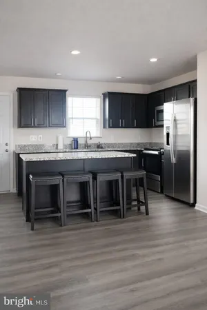 a kitchen with kitchen island stainless steel appliances a table chairs sink and cabinets