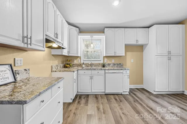 a kitchen with granite countertop a sink and a white wooden cabinets