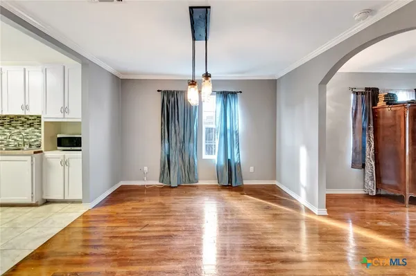 a view of a livingroom with wooden floor and a kitchen space