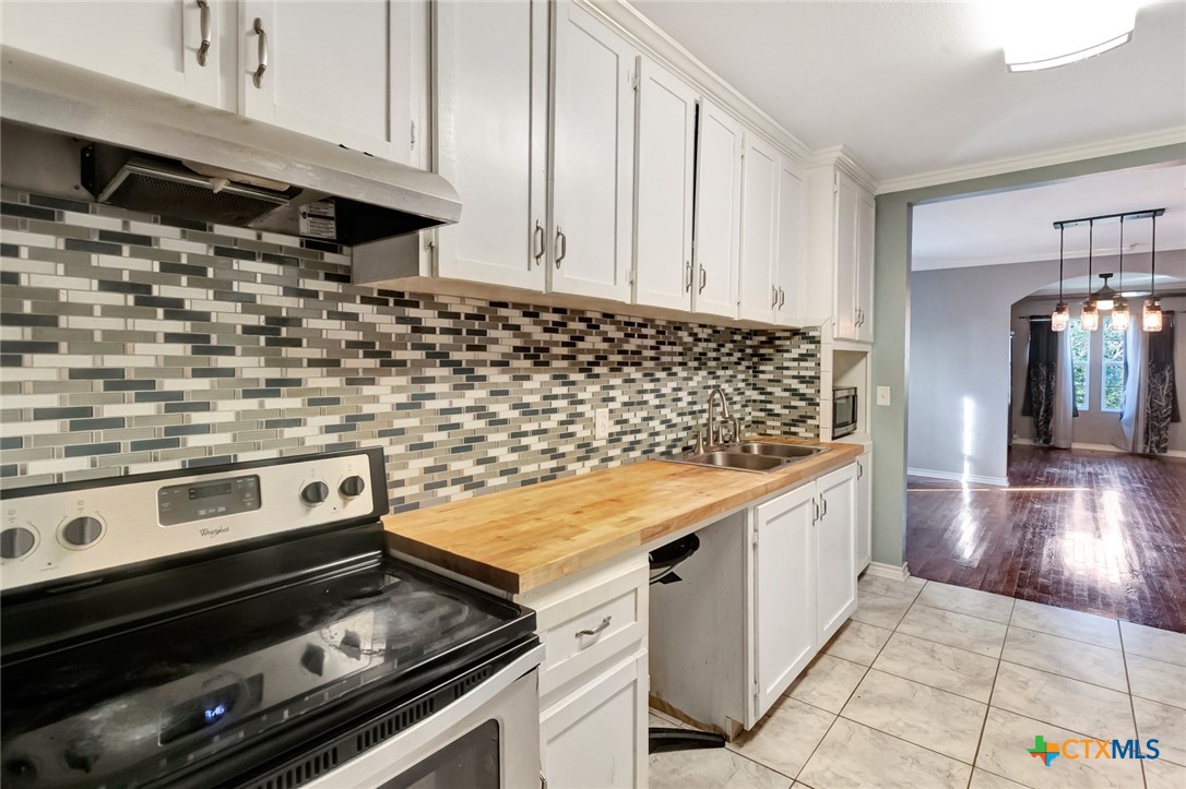 1303 East North Street Victoria, TX 77901 - Photo 16 of 36 a kitchen with a stove and white cabinets