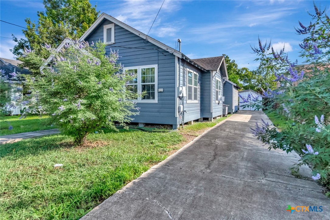 1303 East North Street Victoria, TX 77901 - Photo 2 of 36 a view of a house with a small yard plants and large tree