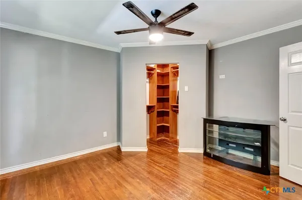 an empty room with wooden floor a ceiling fan and a window