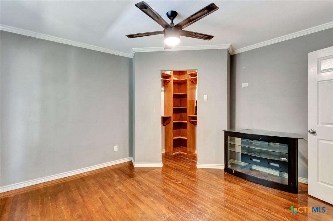 1303 East North Street Victoria, TX 77901 - Photo 23 of 36 an empty room with wooden floor a ceiling fan and a window