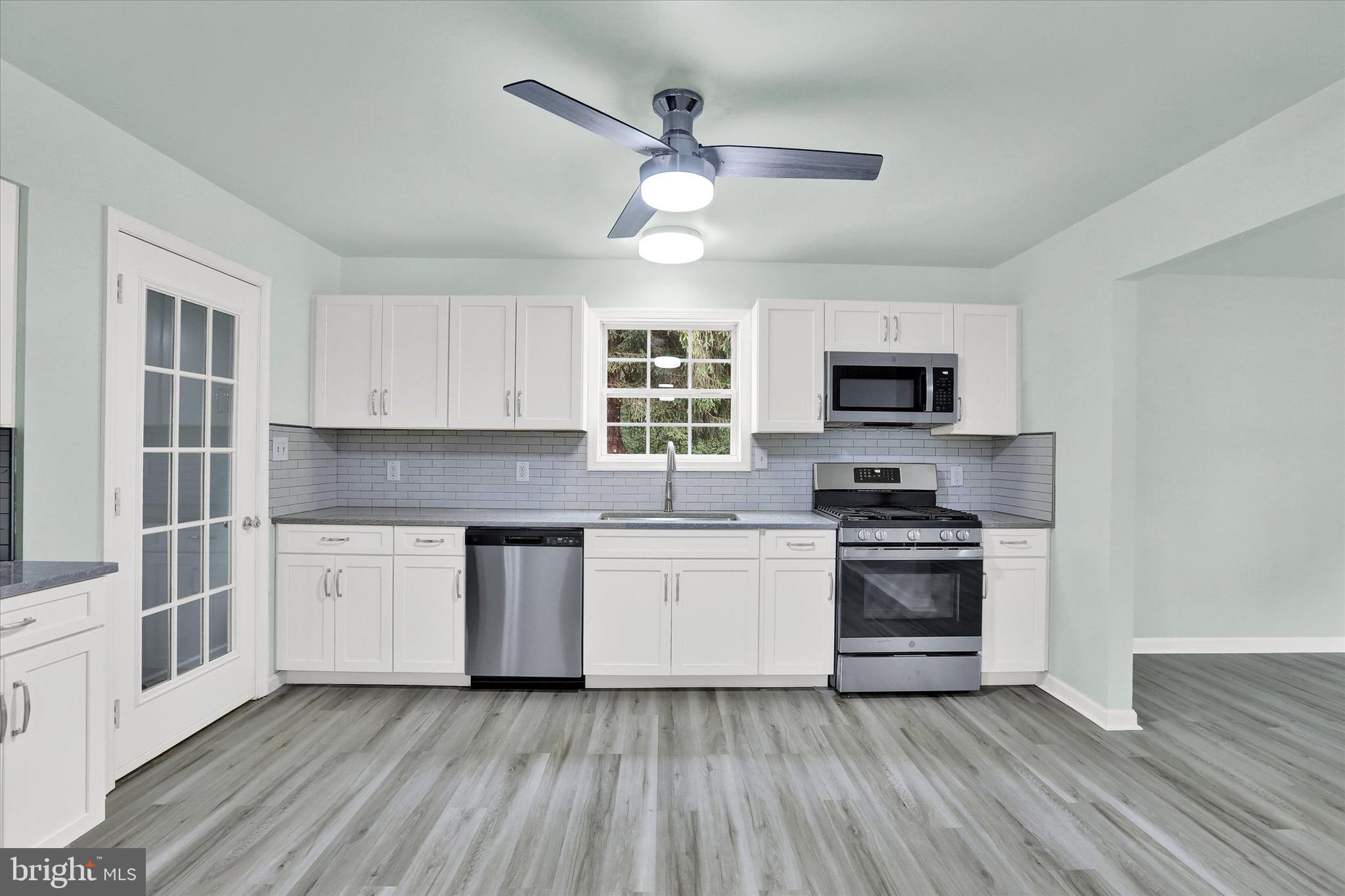 77 Hockamick Road Cookstown, NJ 08511 - Photo 5 of 25 a kitchen with granite countertop a stove top oven a sink dishwasher a dining table and chairs with wooden floor