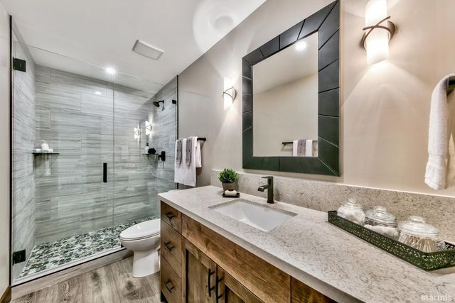 a bathroom with a granite countertop sink a toilet a mirror and shower
