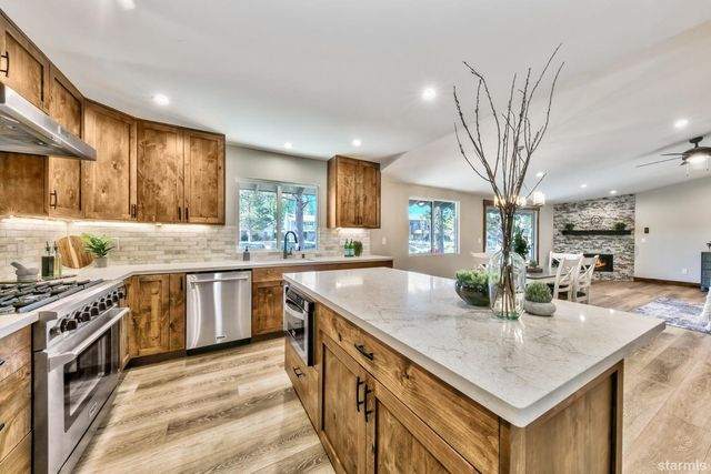 a kitchen with stainless steel appliances granite countertop a sink a stove and a wooden cabinets