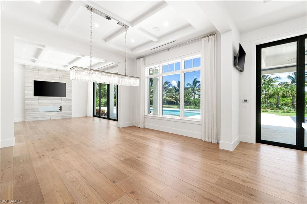171 North Street Naples, FL 34108 - Photo 8 of 50 Unfurnished living room with beamed ceiling, a fireplace, french doors, light parquet floors, and coffered ceiling
