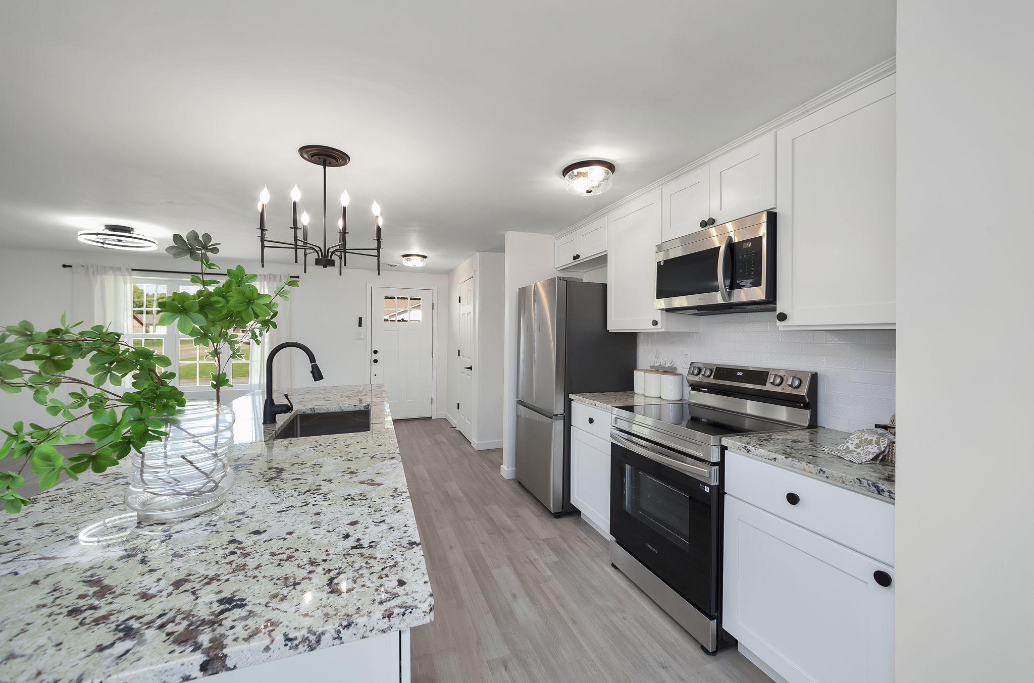 a kitchen with granite countertop a stove a sink and a microwave