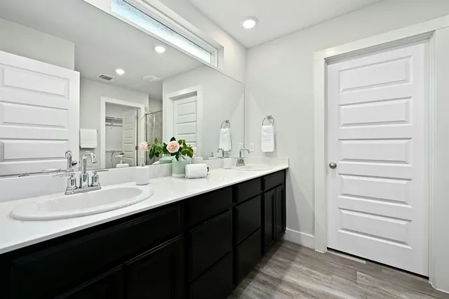a bathroom with a double vanity sink a mirror and a bathtub