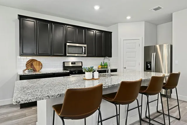 a kitchen with granite countertop wooden cabinets dining table and stainless steel appliances
