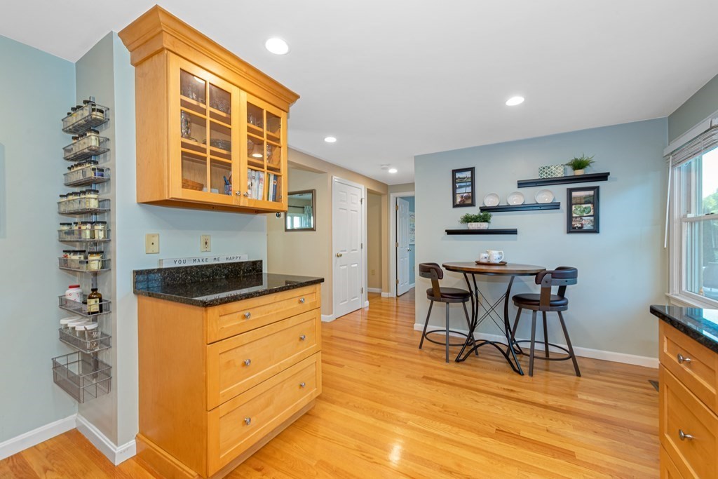 24 Fountain Road Arlington, MA 02476 - Photo 25 of 42 a kitchen with granite countertop a stove a sink a dining table and chairs with wooden floor
