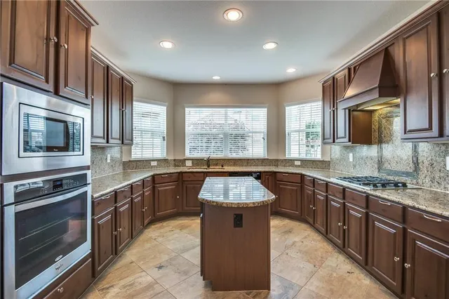 a large kitchen with stainless steel appliances granite countertop a stove sink microwave and window