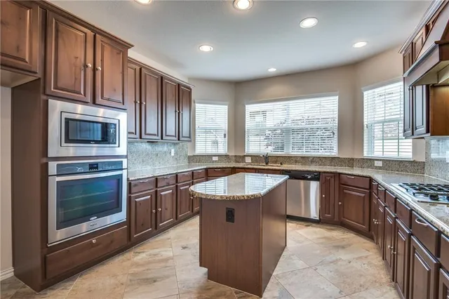 a kitchen with kitchen island granite countertop a sink stove and cabinets
