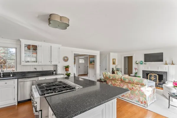 a kitchen with granite countertop a stove a sink a refrigerator dining table and chairs