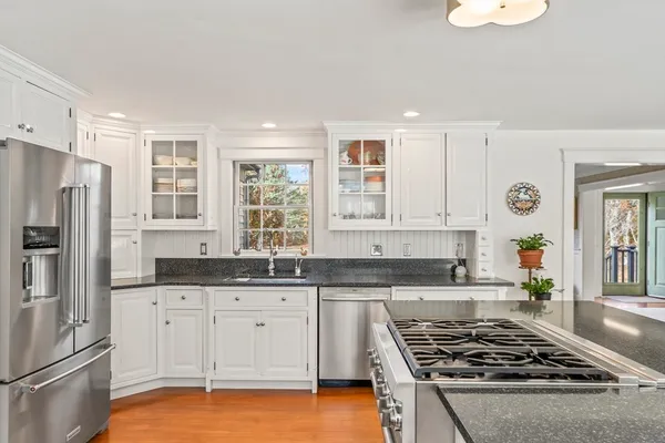 a kitchen with granite countertop a sink stainless steel appliances and white cabinets