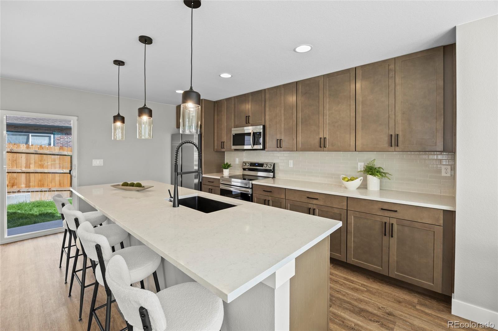 3420 Steele Street Denver, CO 80205 - Photo 14 of 50 a kitchen with a stove a sink a microwave a center island and cabinets