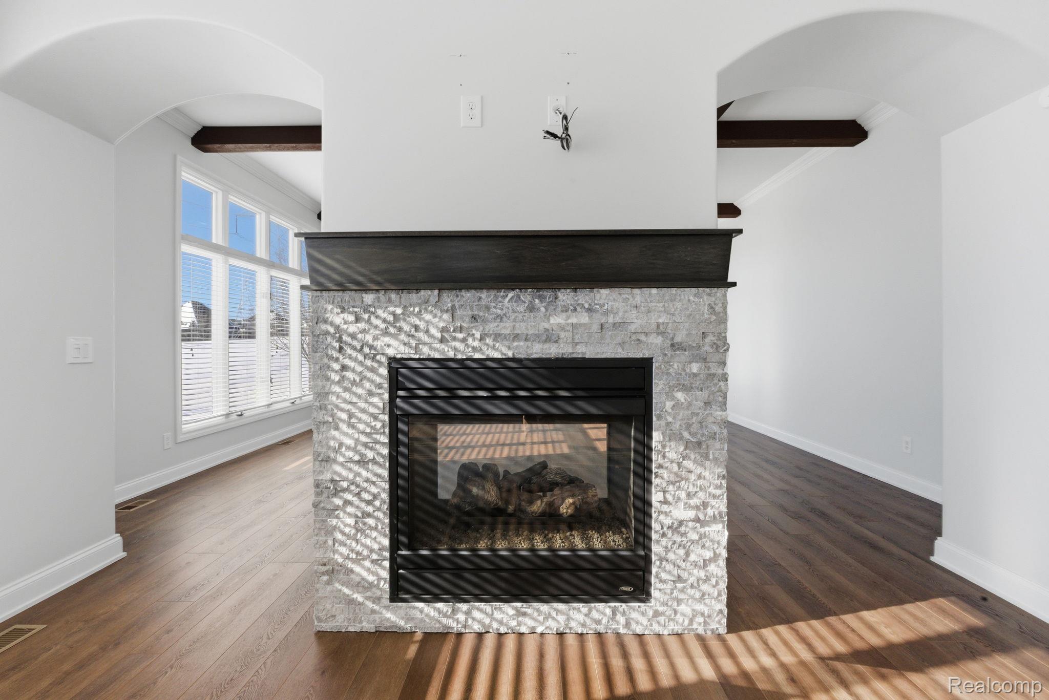 8844 Ridge Drive Washington, MI 48095 - Photo 4 of 51 Detailed view of beamed ceiling, arched walkways, wood finished floors, and a stone fireplace