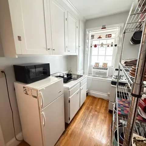 a kitchen with cabinets appliances wooden floor and a window