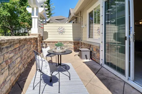 a patio with table and chairs and potted plants
