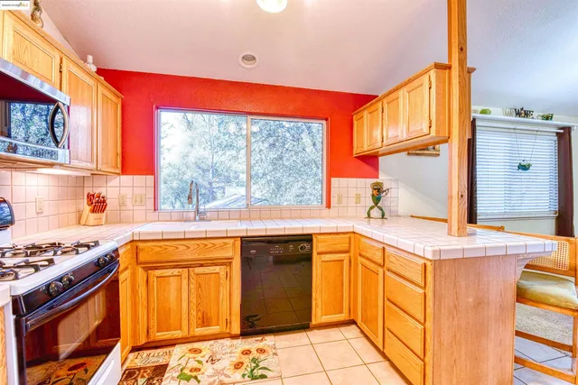 a kitchen with stainless steel appliances granite countertop a refrigerator a stove top oven and a sink with wooden floor