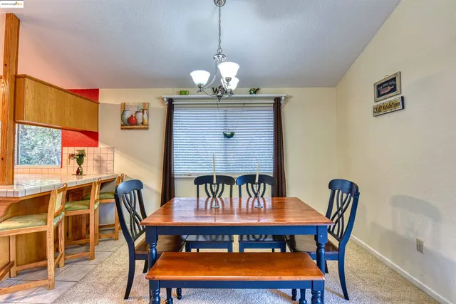 a living room with stainless steel appliances furniture a chandelier and a dining table