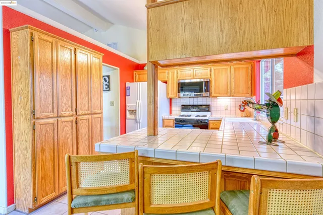a kitchen with stainless steel appliances kitchen island granite countertop a refrigerator a stove top oven and a sink with granite countertops
