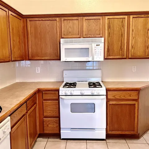 a kitchen with granite countertop a refrigerator and a stove top oven