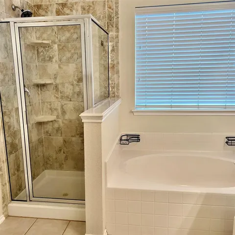 a bathroom with a granite countertop sink mirror bathtub and next to a window